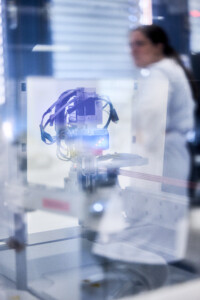 Spiegelung eines Laborger&auml;ts in einer Glasscheibe mit unscharfer Person